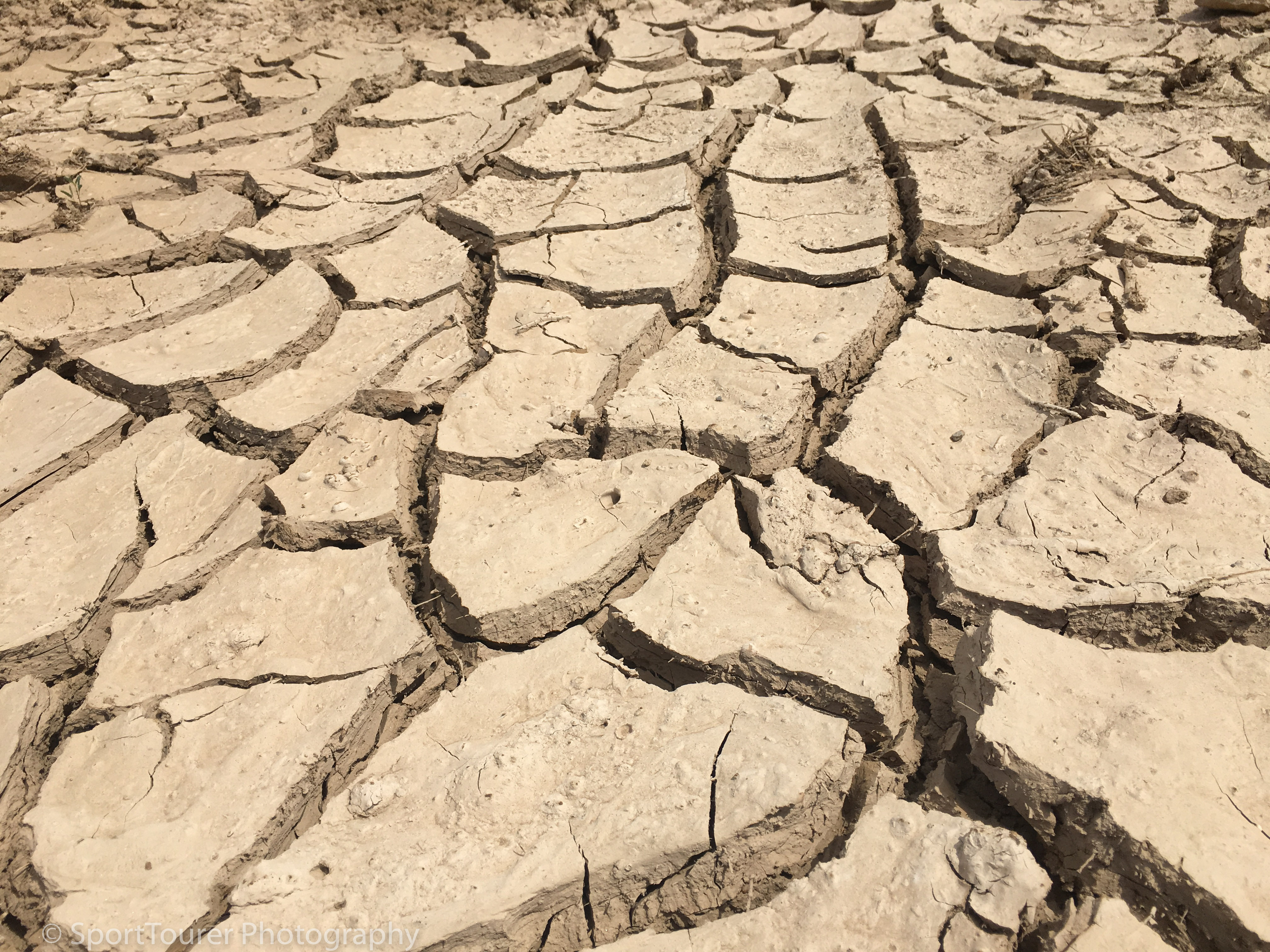  Dry-baked clay/soil in the heat of the day after recent flooding from rainfall along this roadway as I crossed into California from Arizona. 