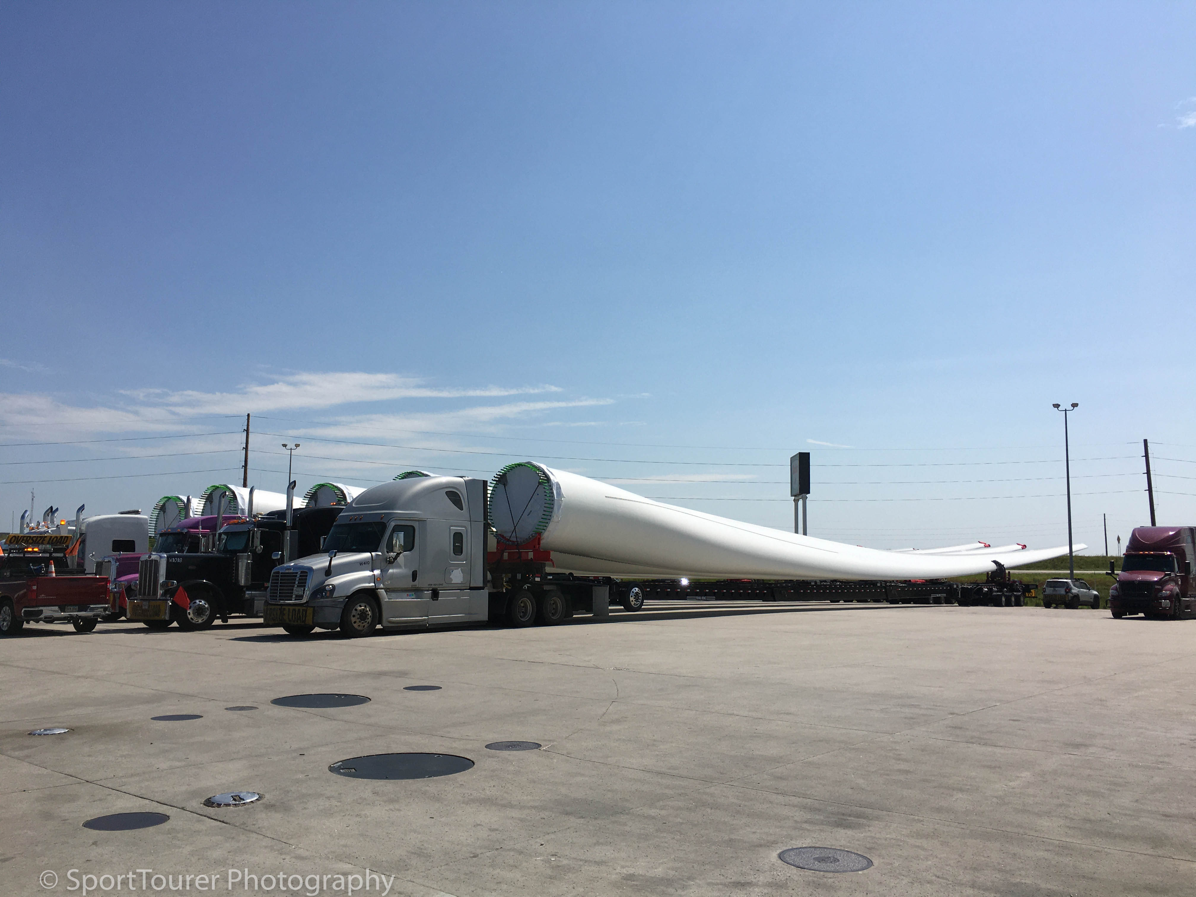  A convoy of Wind Turbine Blades preparing to continue the next segment of their journey. I rode with them for several miles, admiring the technology and skill of the radio-controlled, rear dolly equipment and operators as they navigated their way towards their final wind-farm destination. 